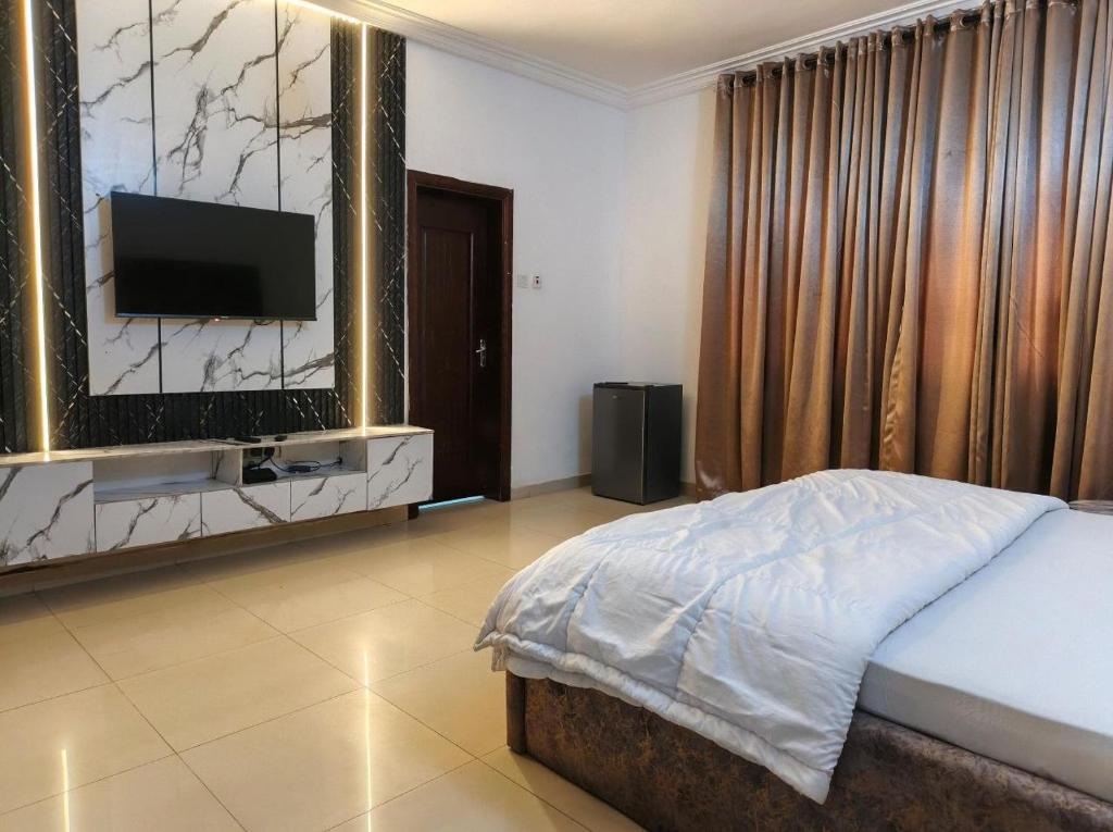 a bedroom with a bed and a flat screen tv at Hillmabliz Apartment in Abuja