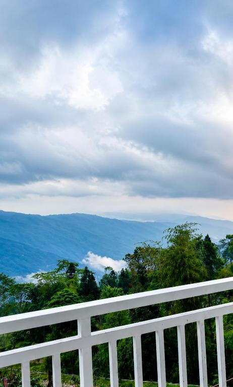 a white fence with a view of the mountains at Sittong Aura in Kurseong