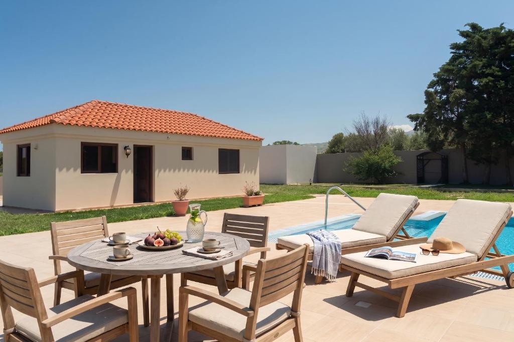 a patio with a table and chairs and a pool at Agios Ioannis Cozy Houses With Private Pool in Tigaki