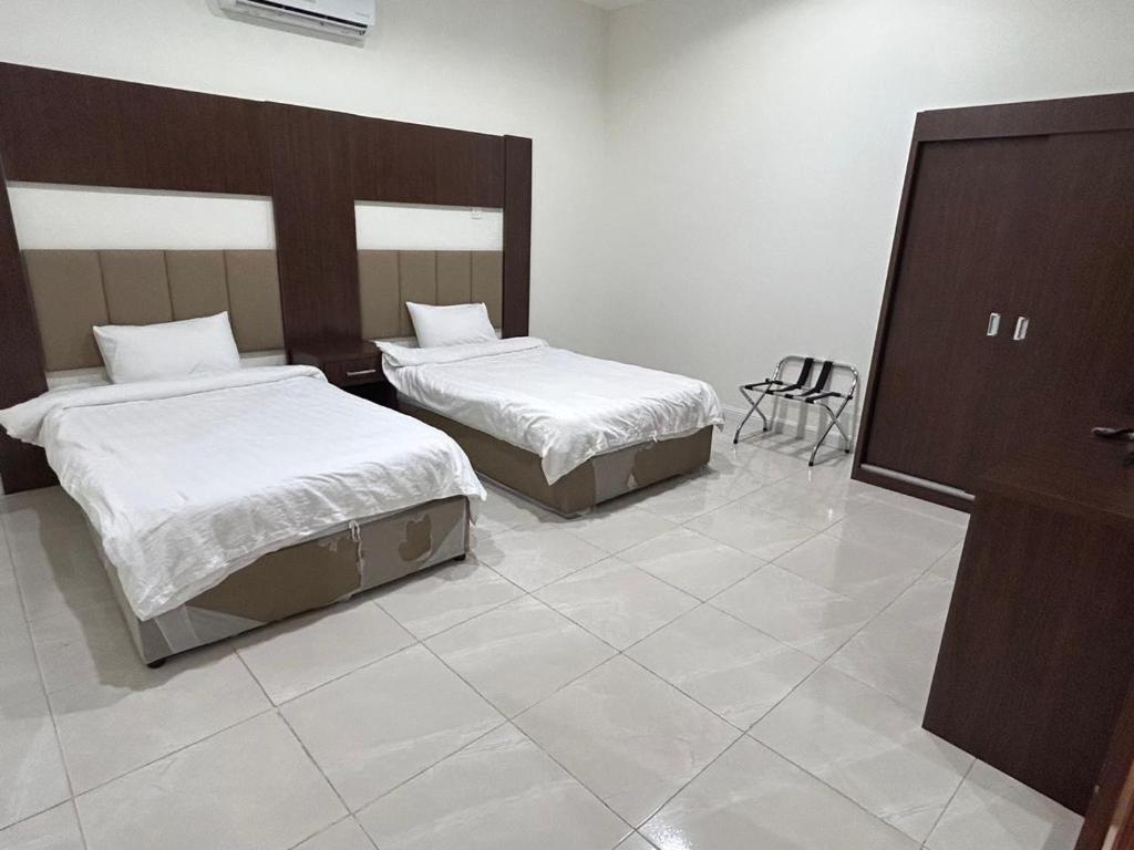 a bedroom with two beds and a chair in it at سرور للشقق المخدومة in Al Baha