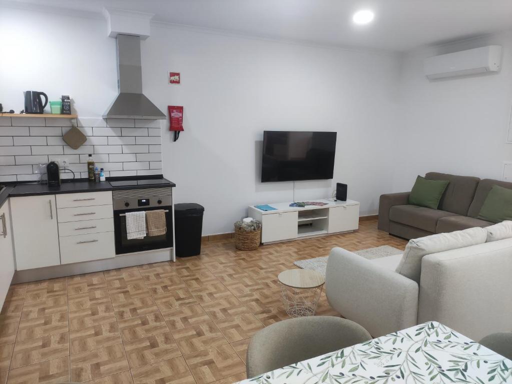 a living room with a couch and a kitchen at Refúgio Machiquense in Machico