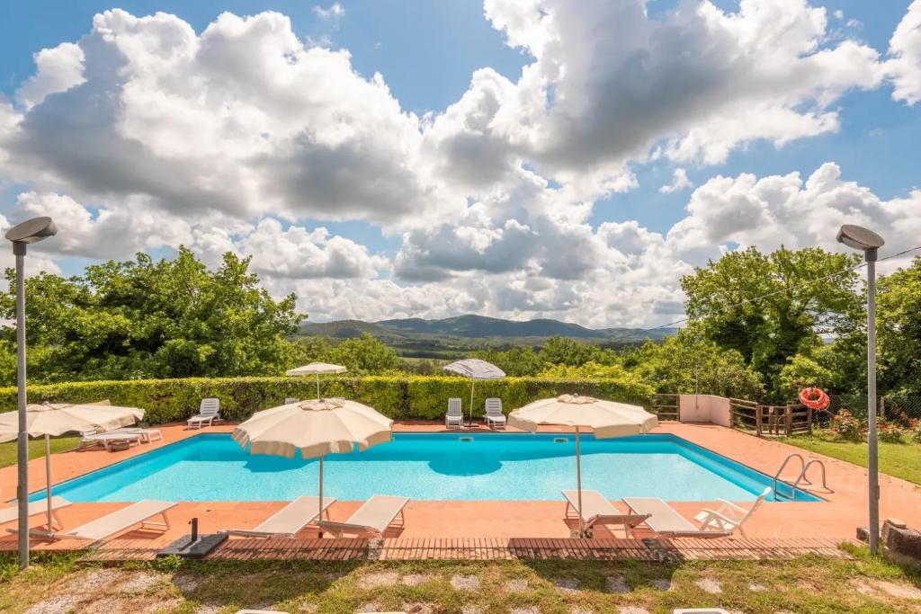a swimming pool with patio chairs and umbrellas at Relax nella jacuzzi in Toscana in Colle di Val d'Elsa