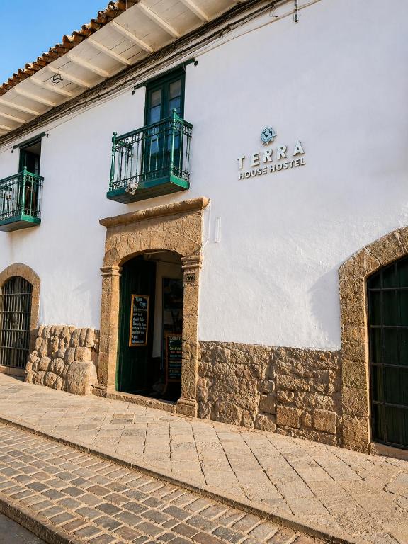 a white building with a door and a balcony at Terra House Hostel in Cusco
