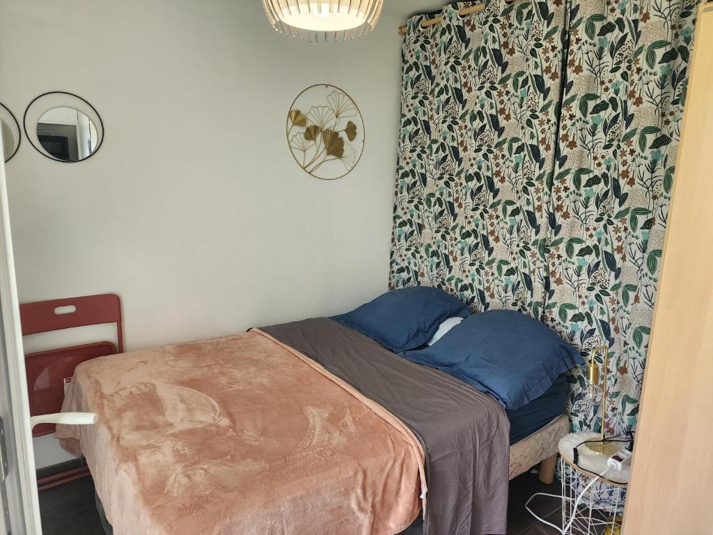 a small bedroom with a bed with blue pillows at Studio cosy sans vis-à-vis in Vernon