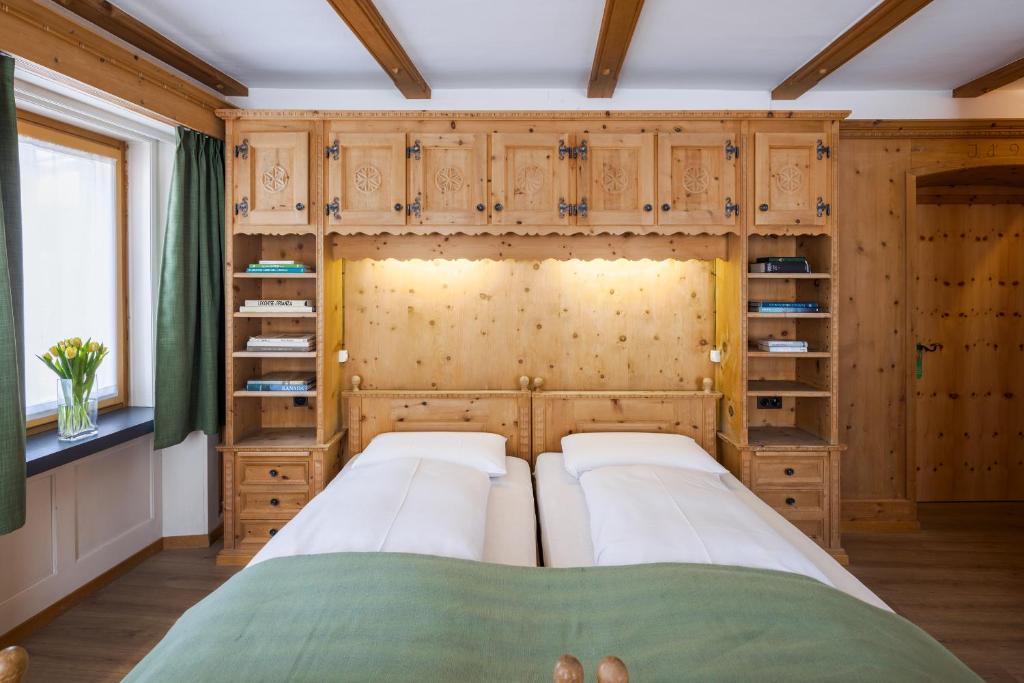 a bedroom with two beds and wooden cabinets at Hotel Alpina in Zernez
