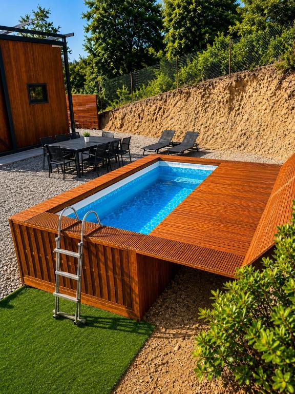 a swimming pool with a wooden deck and a table at Green House in Llagostera