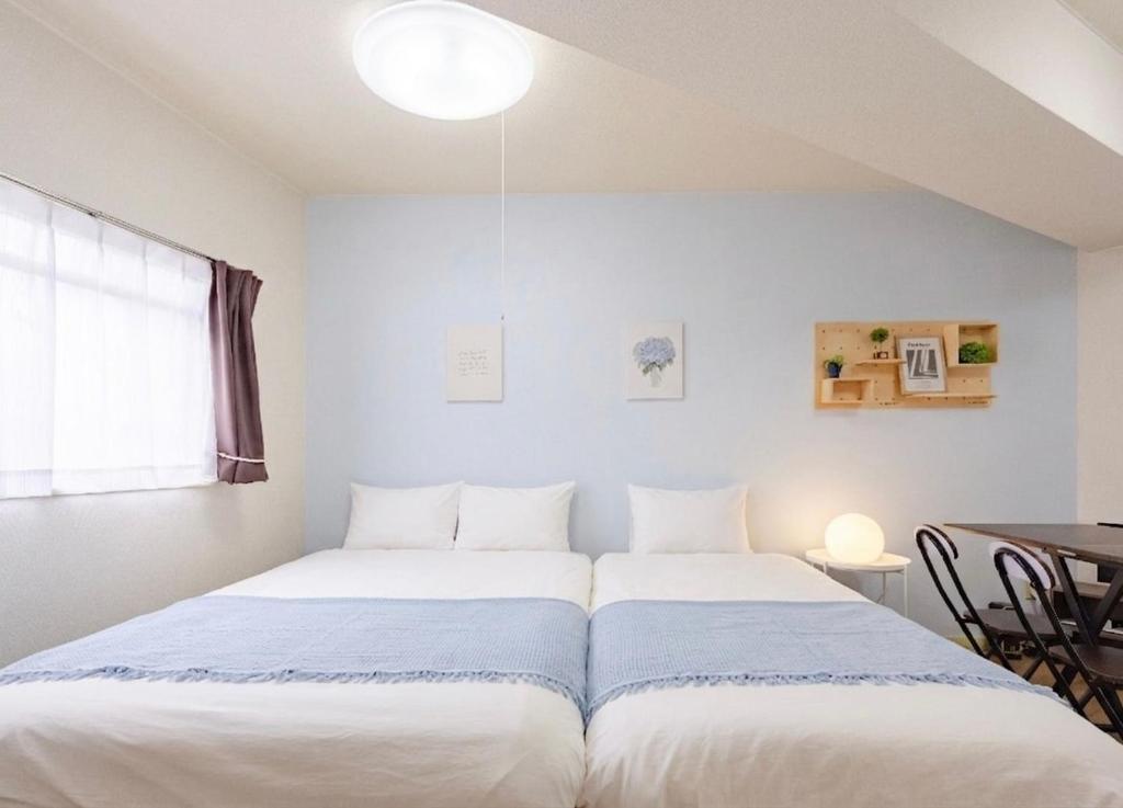 a bedroom with two beds and a table in it at Orange Stay Matsuyama in Matsuyama