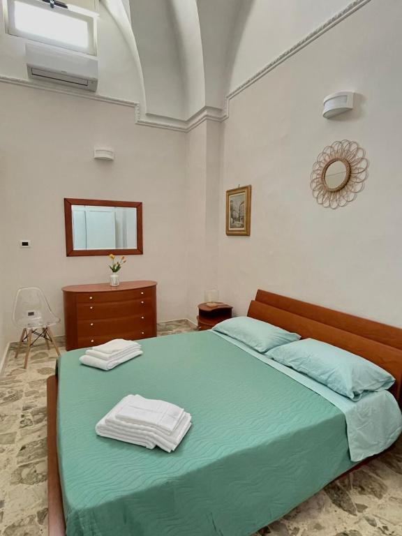 a bedroom with a green bed with two towels on it at Domus Solis Salento in Campi Salentina