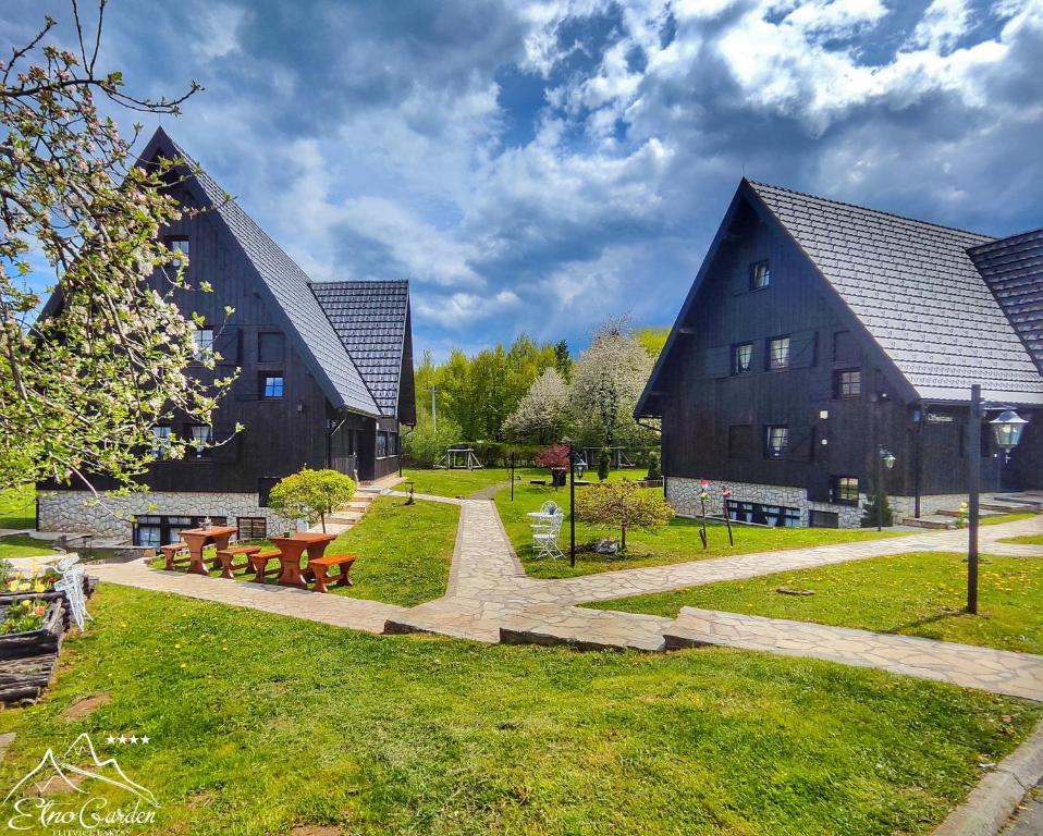 a building with two buildings and a park with benches at Green Garden Plitvice lakes in Plitvica Selo