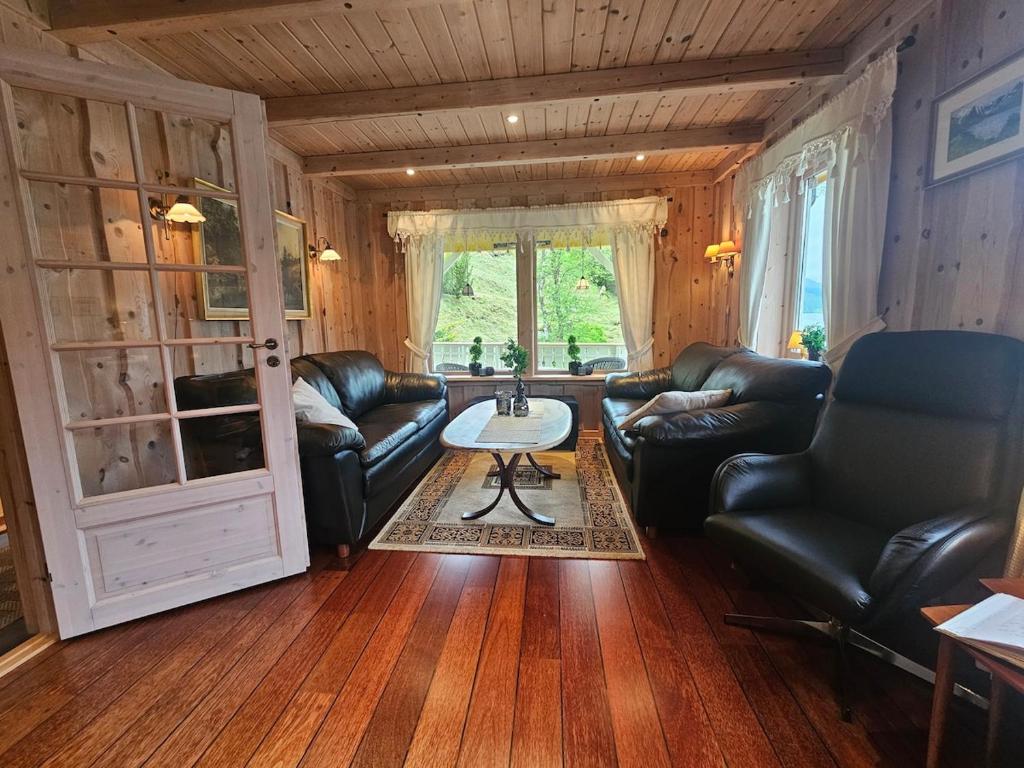 a living room with leather furniture and a table at Huset ved Dalsfjorden in Helle