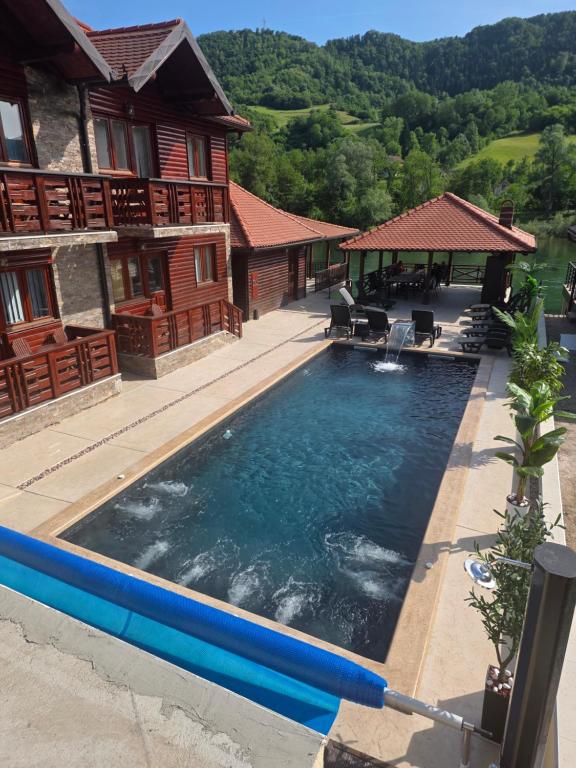 a swimming pool in front of a house at Apartmani ODMOR NA DRINI in Ljubovija