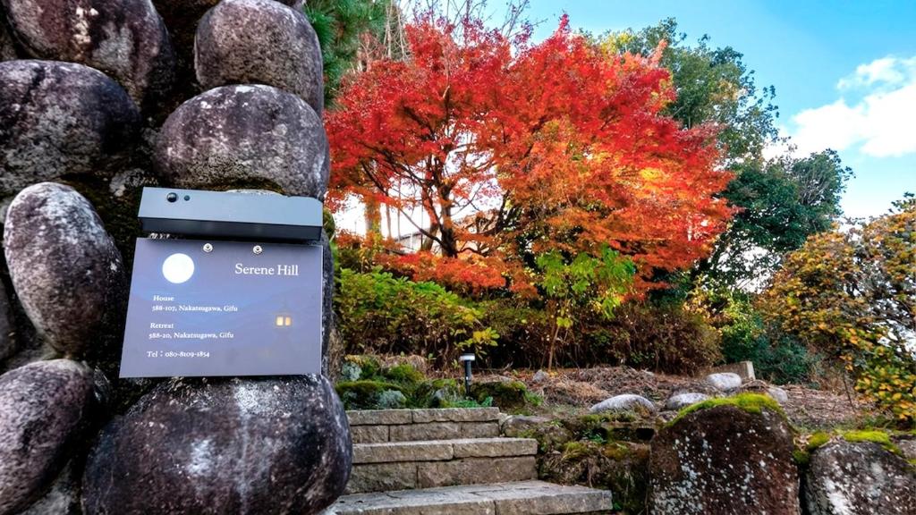 a rock statue with a sign on it in a garden at Serene Hill Retreat in Nakatsugawa