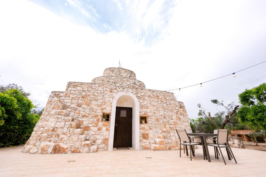 a small stone building with a table and chairs at Masseria La Vecchia Lamia in San Vito dei Normanni