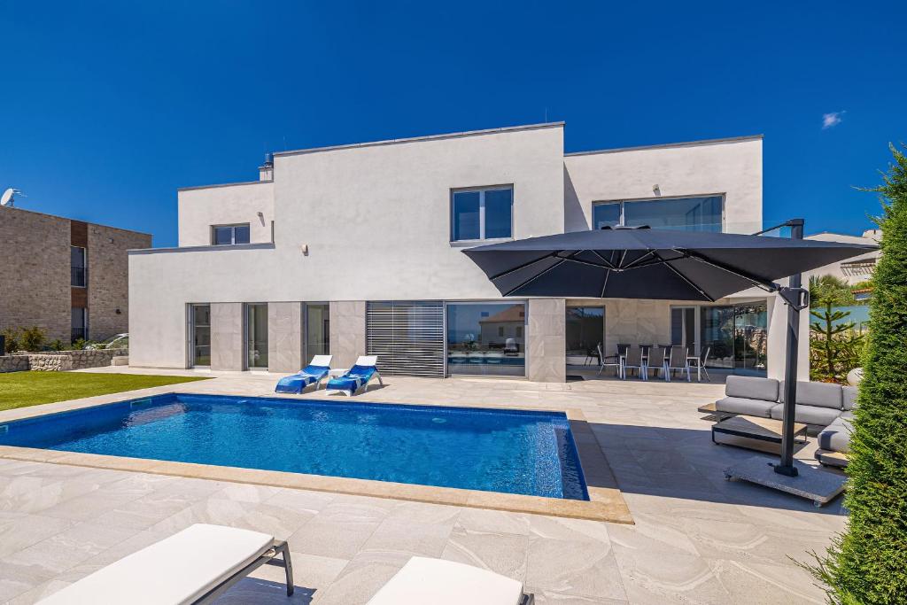 a house with a swimming pool and an umbrella at Villa SIA with private pool in Krk