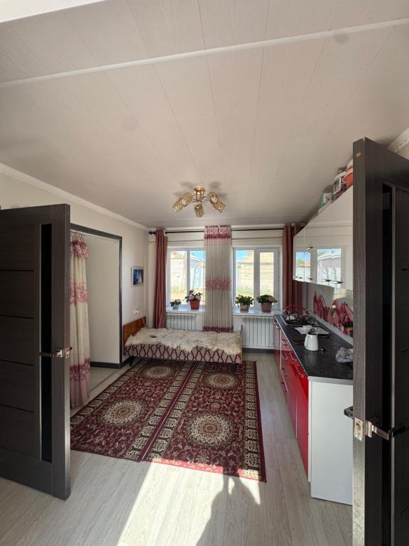 a large kitchen with a bed and a large rug at Bereke guest house in Bokonbayevo