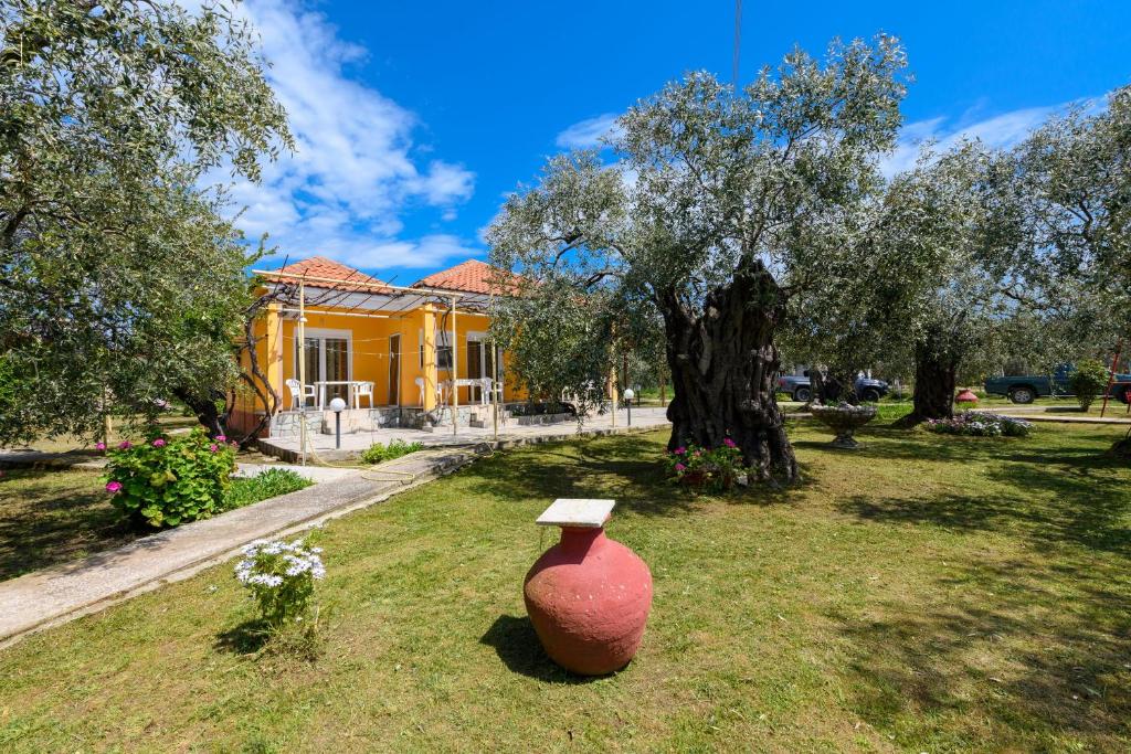 a large vase sitting in the grass in front of a yellow house at Qyra Studios in Skala Rachoniou