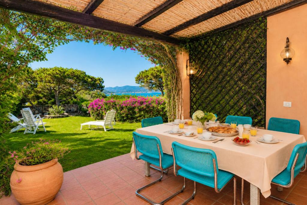 a table and chairs on a patio with a garden at Caprifogli Townhouse Close to the Beach in Baja Sardinia