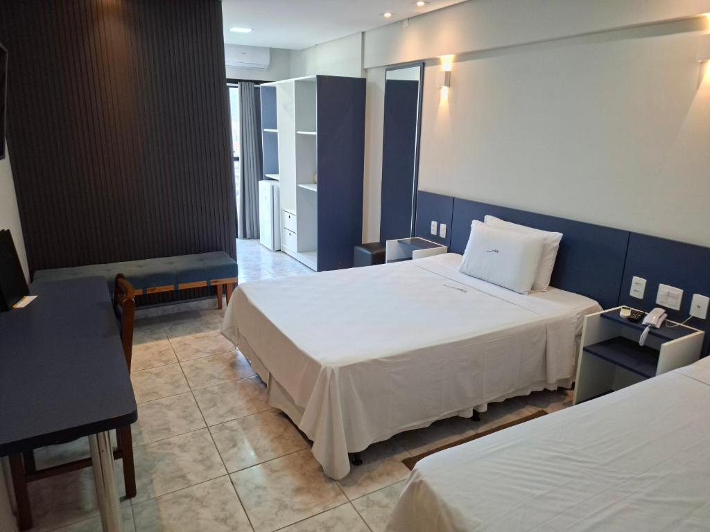 a bedroom with two beds and a blue wall at HOTEL ROTA DO SOL in Praia Grande