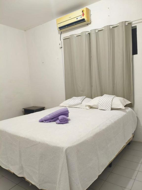 a bedroom with a large white bed with purple pillows at Pousada Bom Jesuss in Juazeiro do Norte