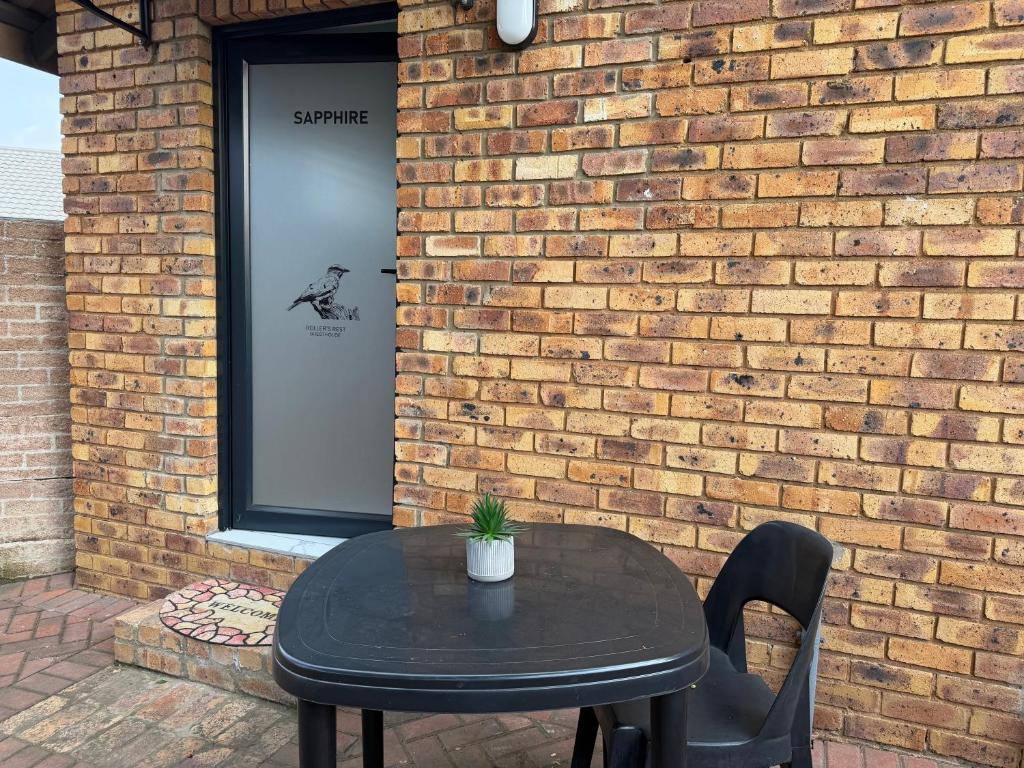 a black table and chairs in front of a brick wall at Rollers Rest Guesthouse in Boksburg