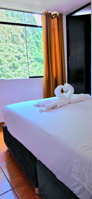 a bed in a room with a large window at Hostal Mónaco in Machu Picchu