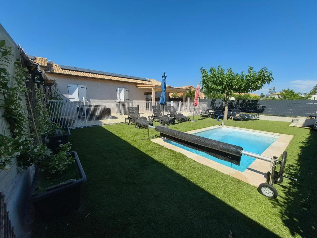a backyard with a swimming pool and grass at En Ardèche, maison de vacances l'Odyssée climatisée avec sa piscine privée et chauffée in Joyeuse