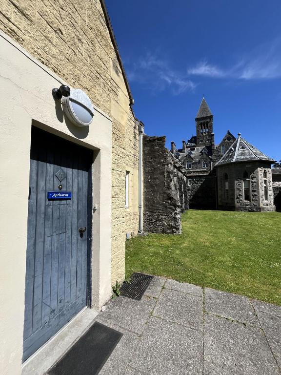 a building with a blue door and a church at Ancluaran - Moat House 10 in Fort Augustus