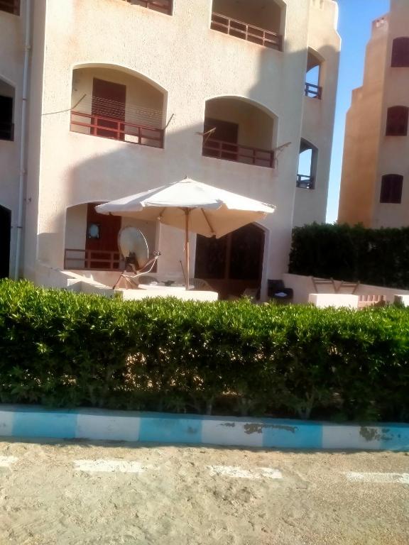 a white umbrella sitting in front of a building at غرفتين و ترأس بالاندلسية in Marsa Matruh