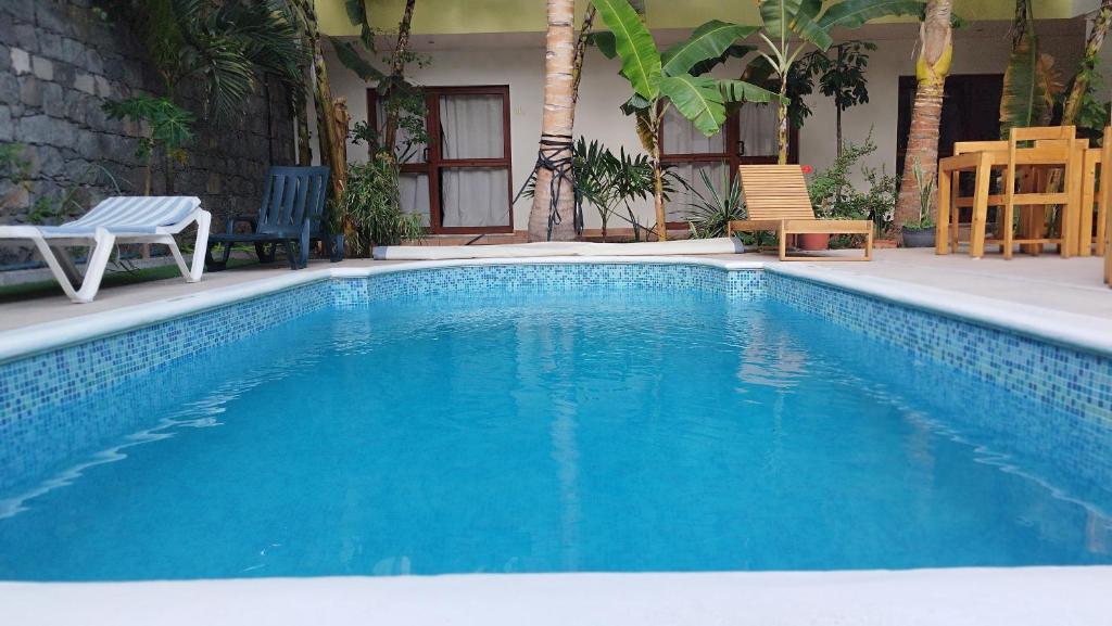 a blue swimming pool with two chairs and a house at Residencial Lela d'Fermina in Pombas