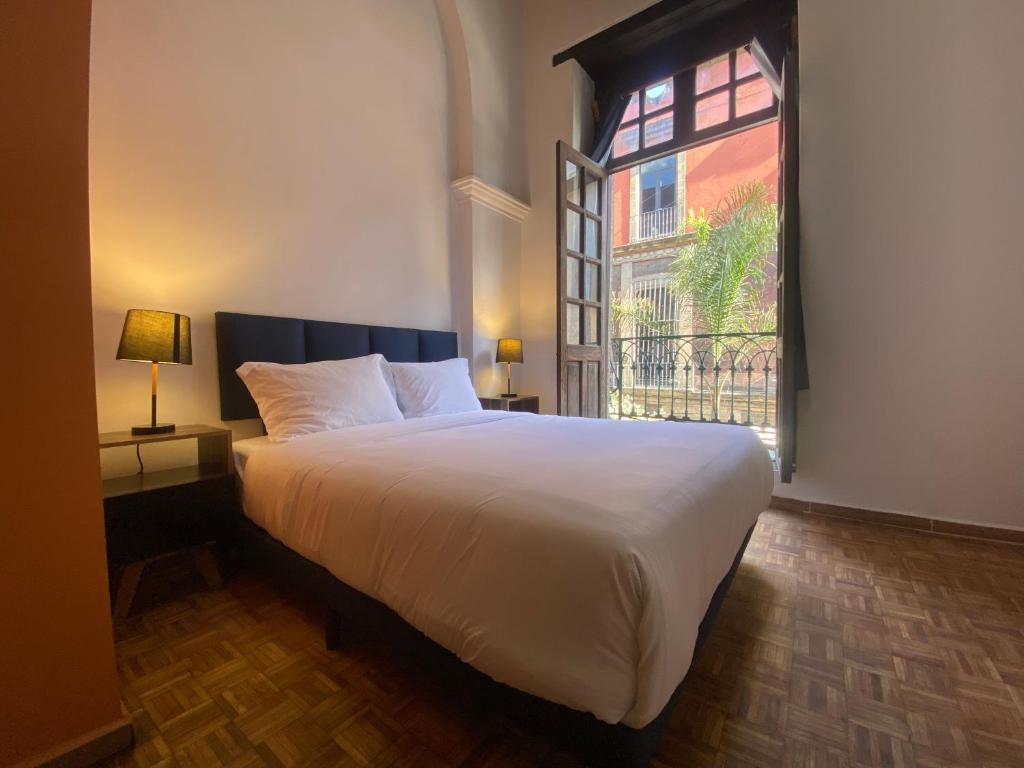 a bedroom with a large white bed with a window at Casa Regina CDMX in Mexico City