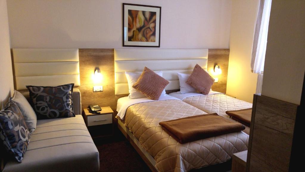 um quarto de hotel com duas camas e um sofá em Hotel Čile em Kolašin