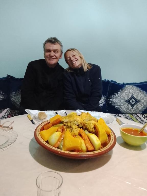 a man and woman sitting at a table with a plate of food at Appartement chez bennouri in Telouet