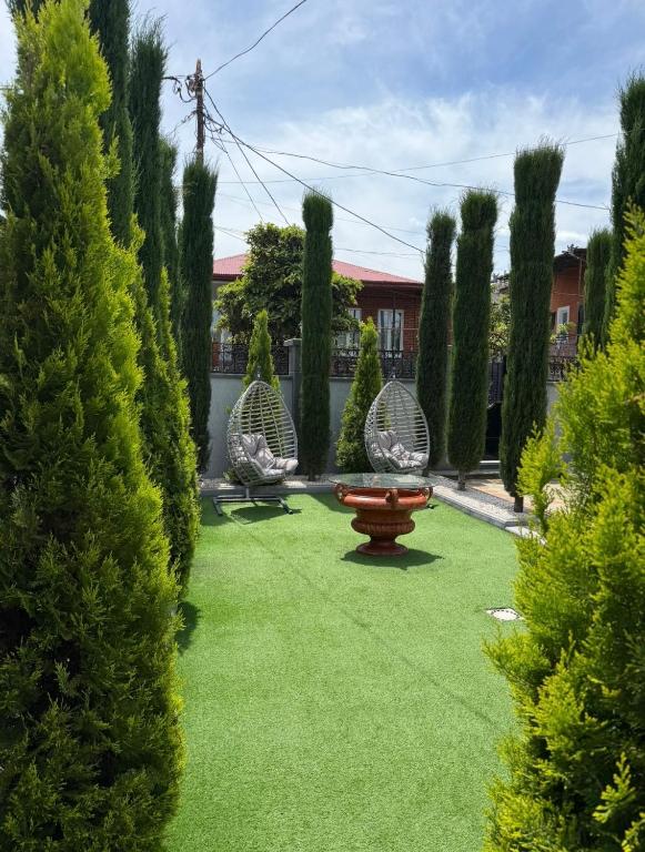 a garden with three chairs and a table and trees at Villa Cypress in Kutaisi