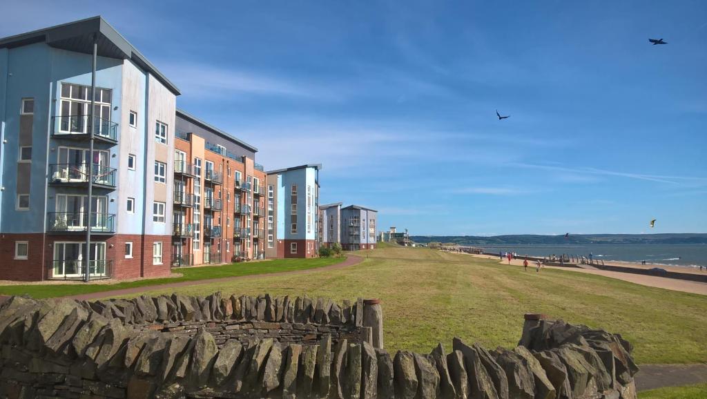 a row of apartment buildings next to a stone wall at Coastal Apartments - Wales in Swansea