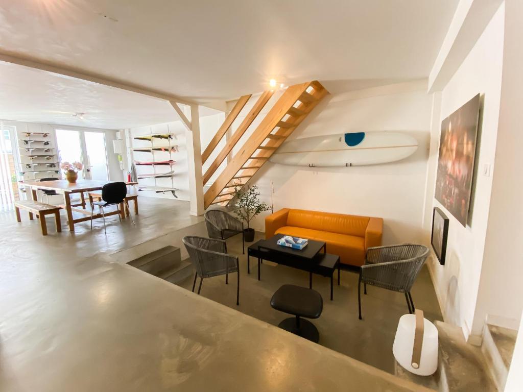 a living room with an orange couch and a table at Koala Surf House, en bord d'Océan, planches de surf et skates à disposition in Hossegor