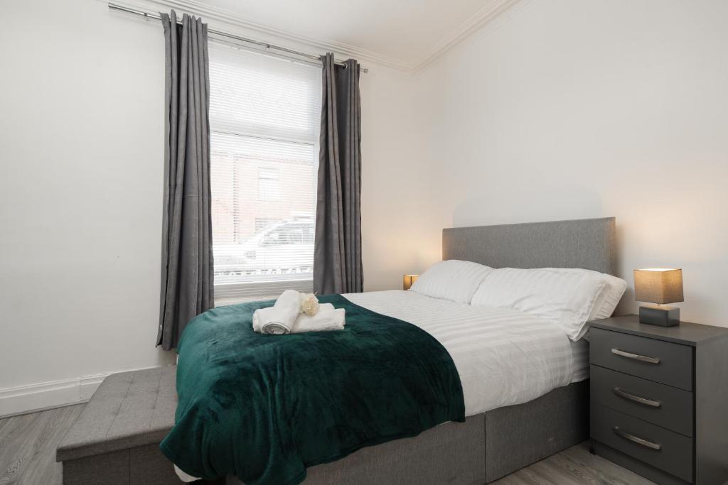a bedroom with a bed with a teddy bear on a green blanket at Denton Luxury Home - Sleep 8 - Speedy Wi-Fi - Free On-Site Parking in Denton