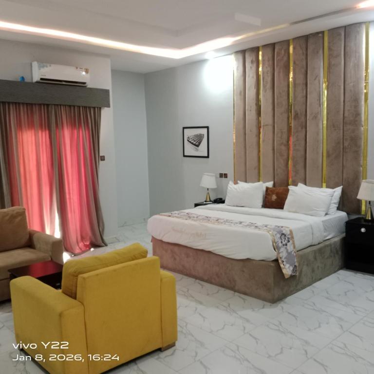 a hotel room with a bed and a yellow chair at Pointax Apartment Lekki in Ilado