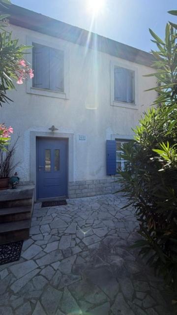 a building with a blue door and a stone courtyard at Pr' Tekcu in Dekani