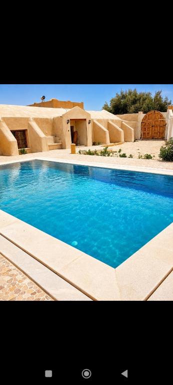 a large blue swimming pool in front of a house at Dar ennoul in Houmt Souk