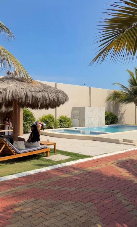 a woman sitting on a bench next to a swimming pool at Hotel La Mar Playas in Playas
