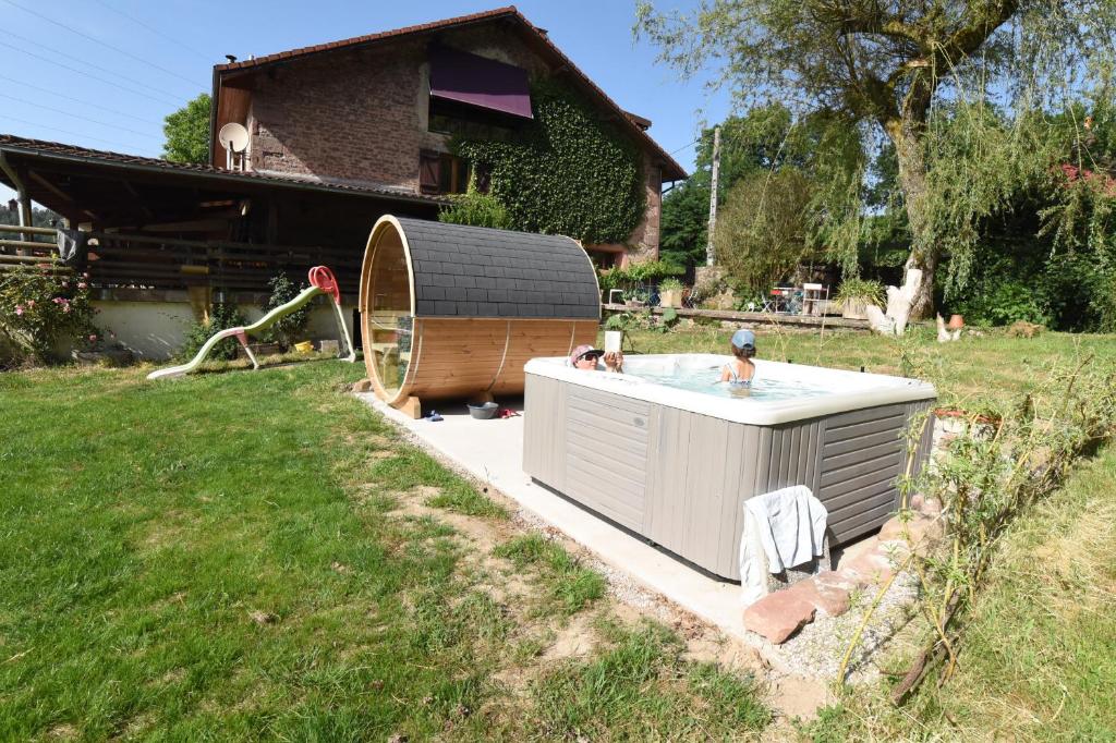 a hot tub in a yard next to a house at Chambres d'hôte Odile et les cycleux Lily in Docelles