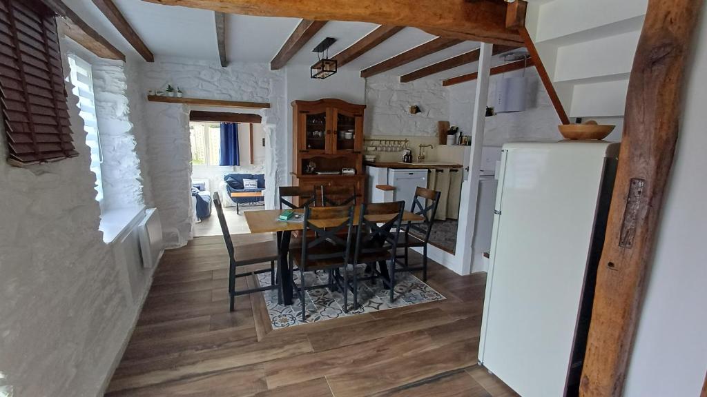 a kitchen and dining room with a table and a refrigerator at Pont Menou Bretagne in Plouégat-Guérand