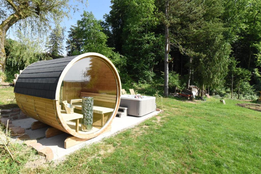 a round wooden tub sitting in a grass field at Gîte en pleine nature in Docelles