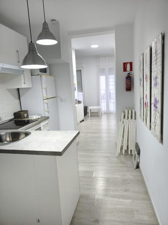 a white kitchen with a counter and a hallway at Apartamentos Teresita in Badajoz