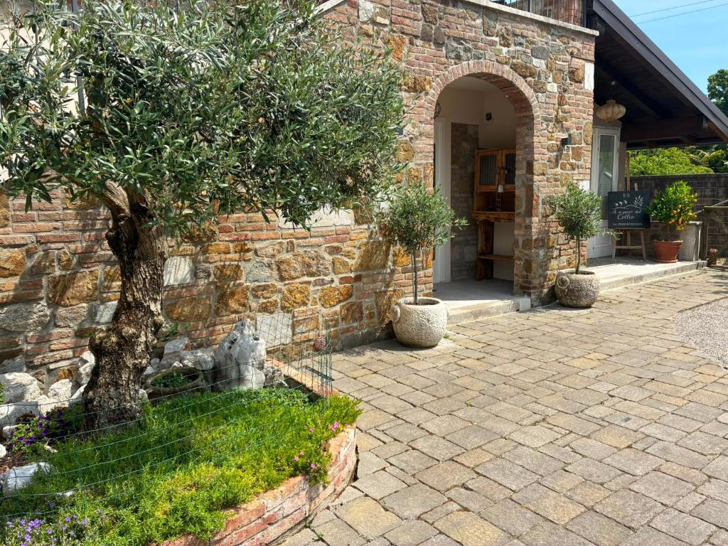 a stone house with a tree in front of it at A un passo dal Collio in Mossa