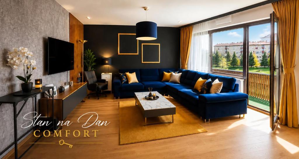 a living room with a blue couch and a large window at Stan na dan Koprivnica-Comfort in Koprivnica