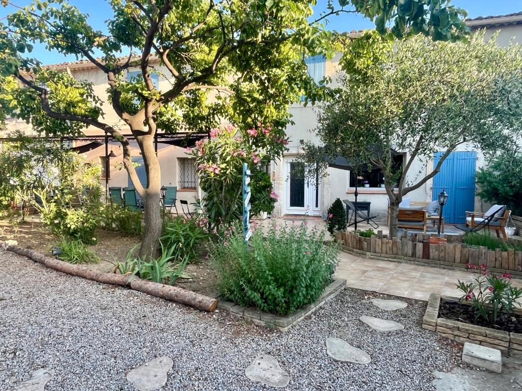 a house with a garden with trees and rocks at Le colibri bleu in Argeliers