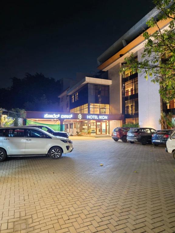 a parking lot with cars parked in front of a building at Hotel Ikon in Hubli