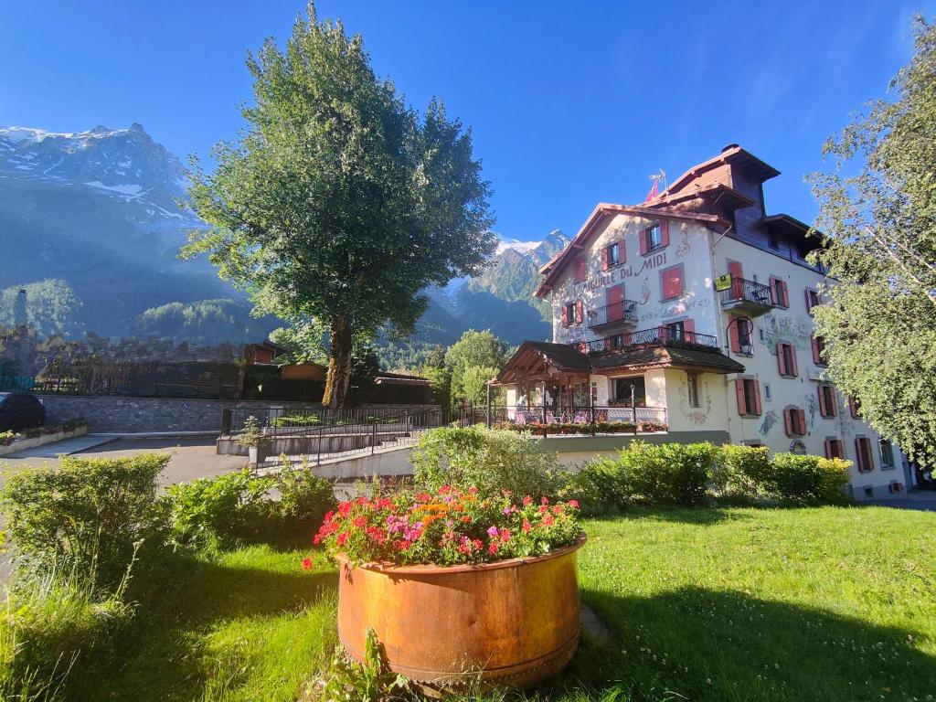 a large white building with flowers in a yard at Aiguille du Midi - Hôtel & Restaurant in Chamonix