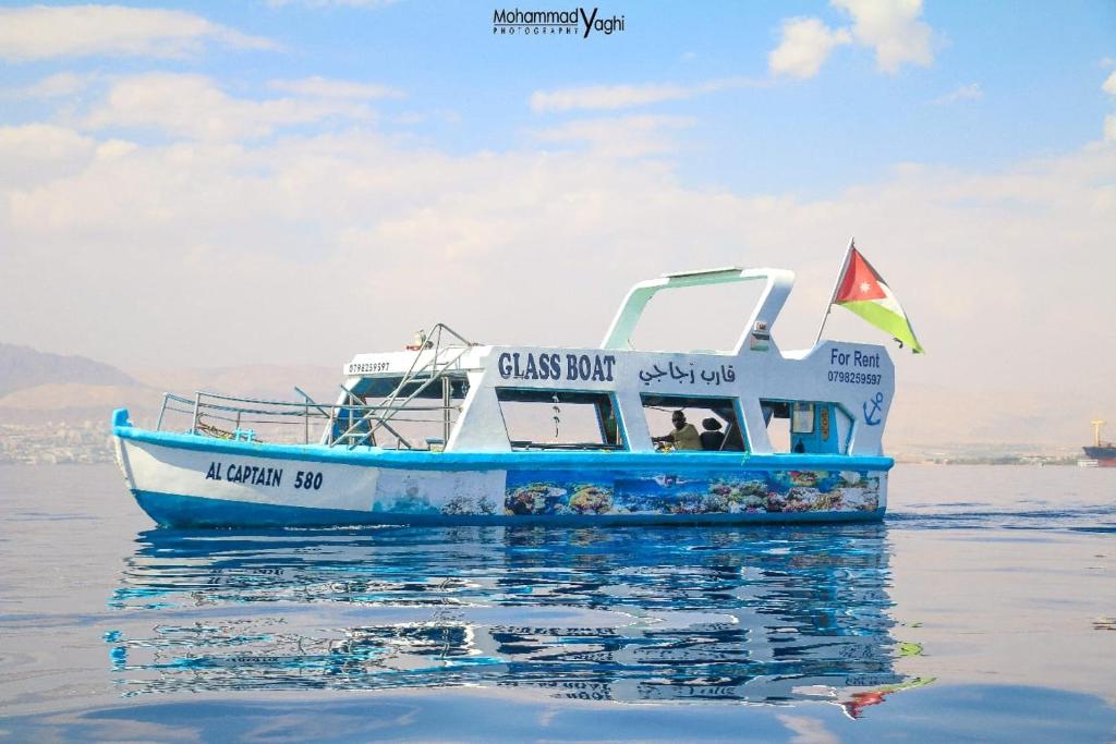 a blue and white boat floating on the water at AlCaptian Glassboat in Aqaba